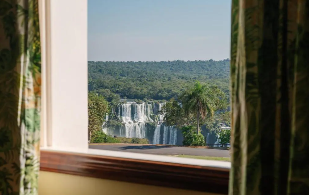The Iguassu Falls seen through an open hotel window framed by curtains